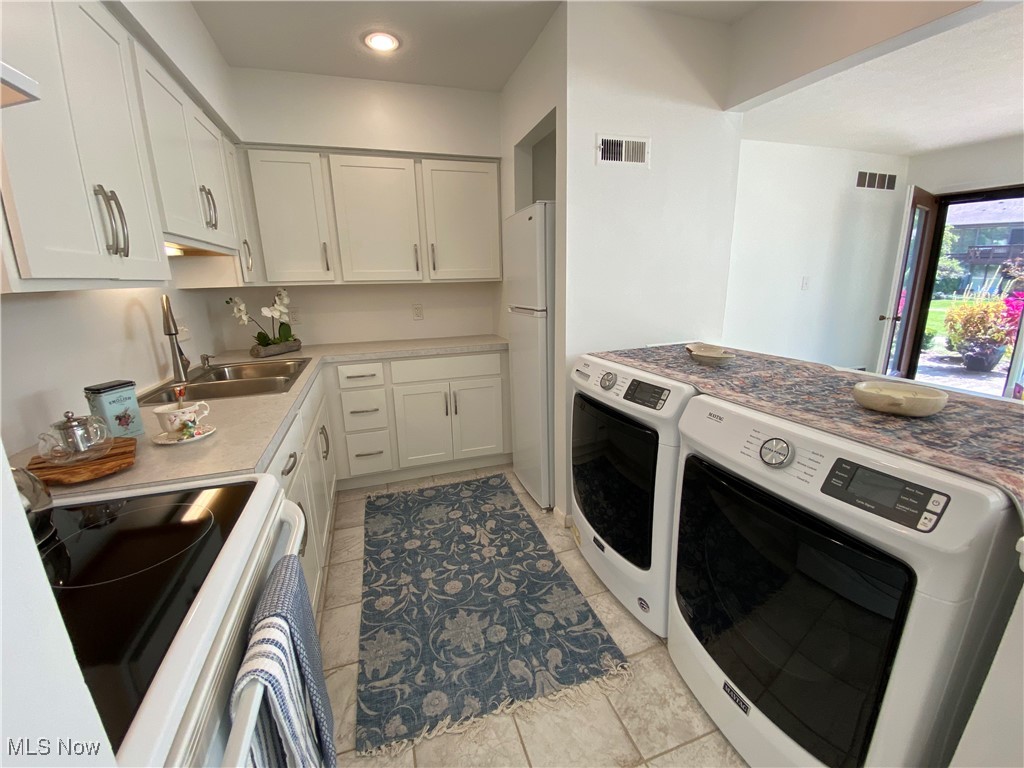 985 Canyon View Road, Unit 102B Northfield, OH 44067 - Photo 8 of 32 Kitchen with white fridge, range, washing machine and clothes dryer, white cabinets, and light tile patterned flooring