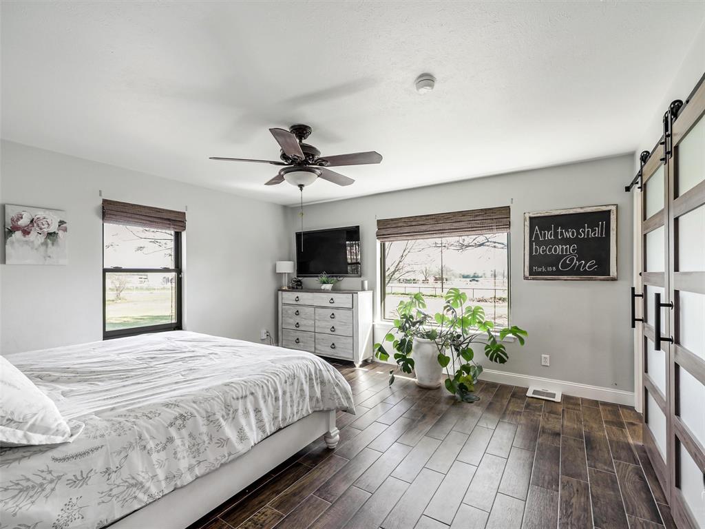 62 Sanders Road Whitesboro, TX 76273 - Photo 11 of 19 The spacious primary bedroom offers abundant natural light, warm wood-look flooring, and a calm, inviting atmosphere.
