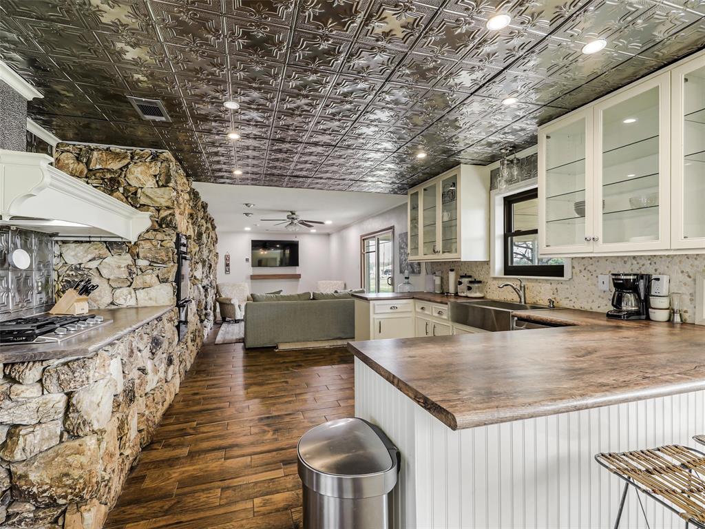 62 Sanders Road Whitesboro, TX 76273 - Photo 5 of 19 The breakfast nook flows seamlessly into the kitchen and secondary living room, where a stunning stone fireplace creates a warm, natural focal point.