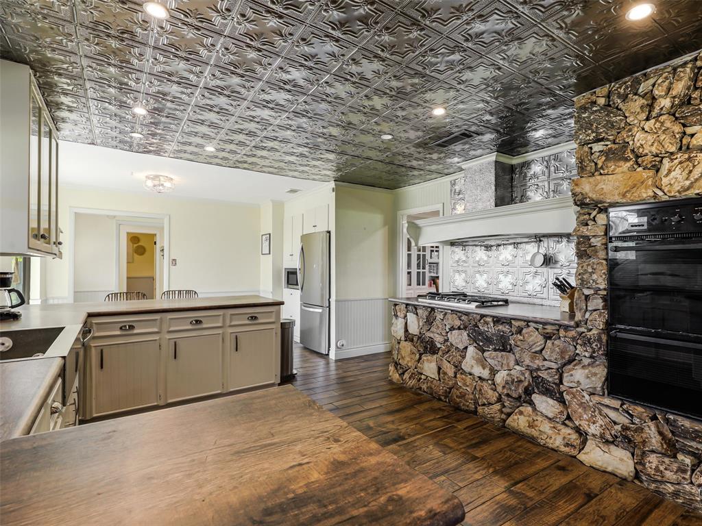 62 Sanders Road Whitesboro, TX 76273 - Photo 6 of 19 The kitchen opens to a striking natural stone feature wall with gas fireplace, complemented by a charming tin ceiling and an open layout designed for effortless entertaining.