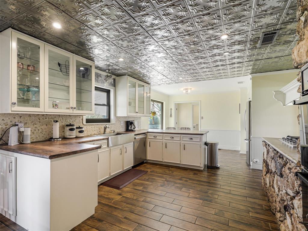 62 Sanders Road Whitesboro, TX 76273 - Photo 7 of 19 Kitchen with a peninsula, glass insert cabinets, dark wood-type flooring, wainscoting, and stainless steel appliances
