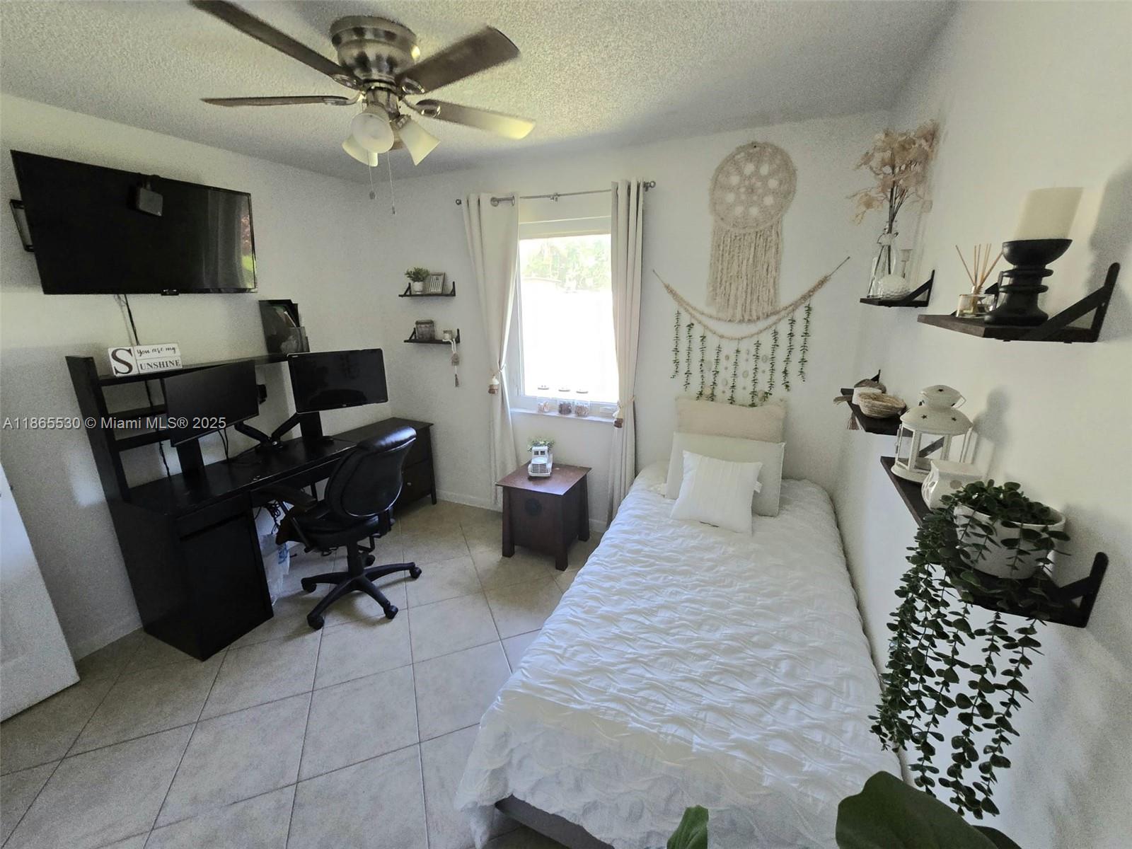 6120 Edwards Road Margate, FL 33063 - Photo 17 of 47 a bedroom with a bed a couch and a flat screen tv