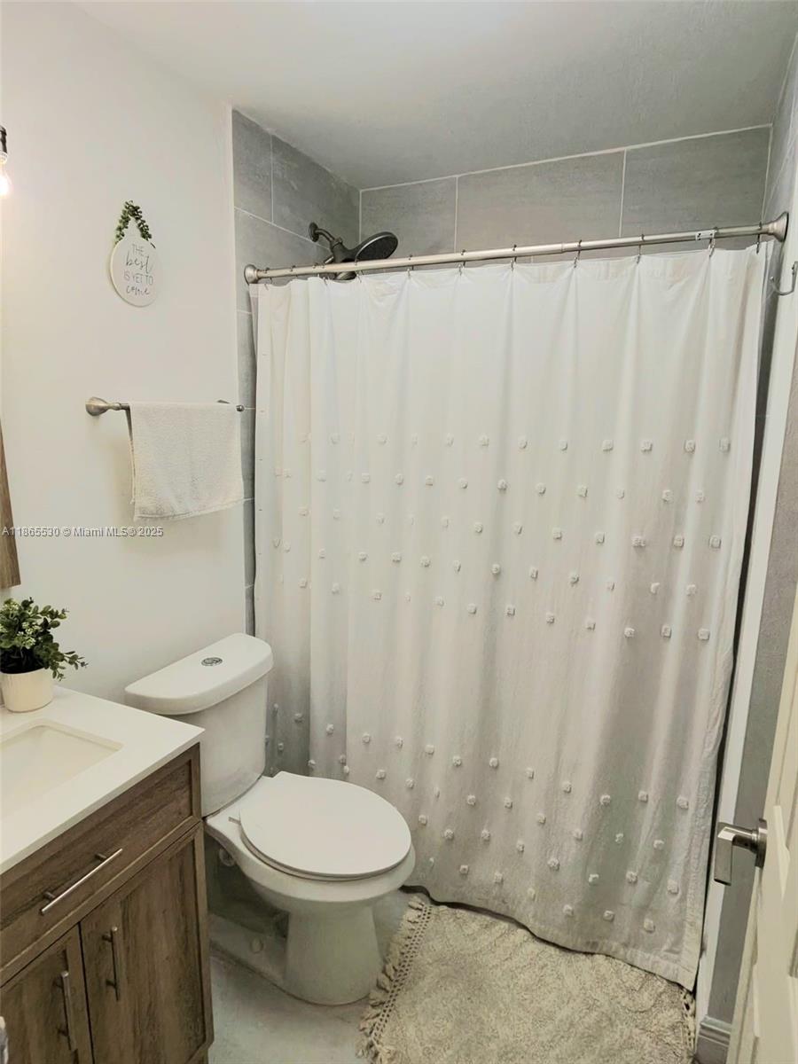 6120 Edwards Road Margate, FL 33063 - Photo 21 of 47 a bathroom with a toilet a sink and curtain