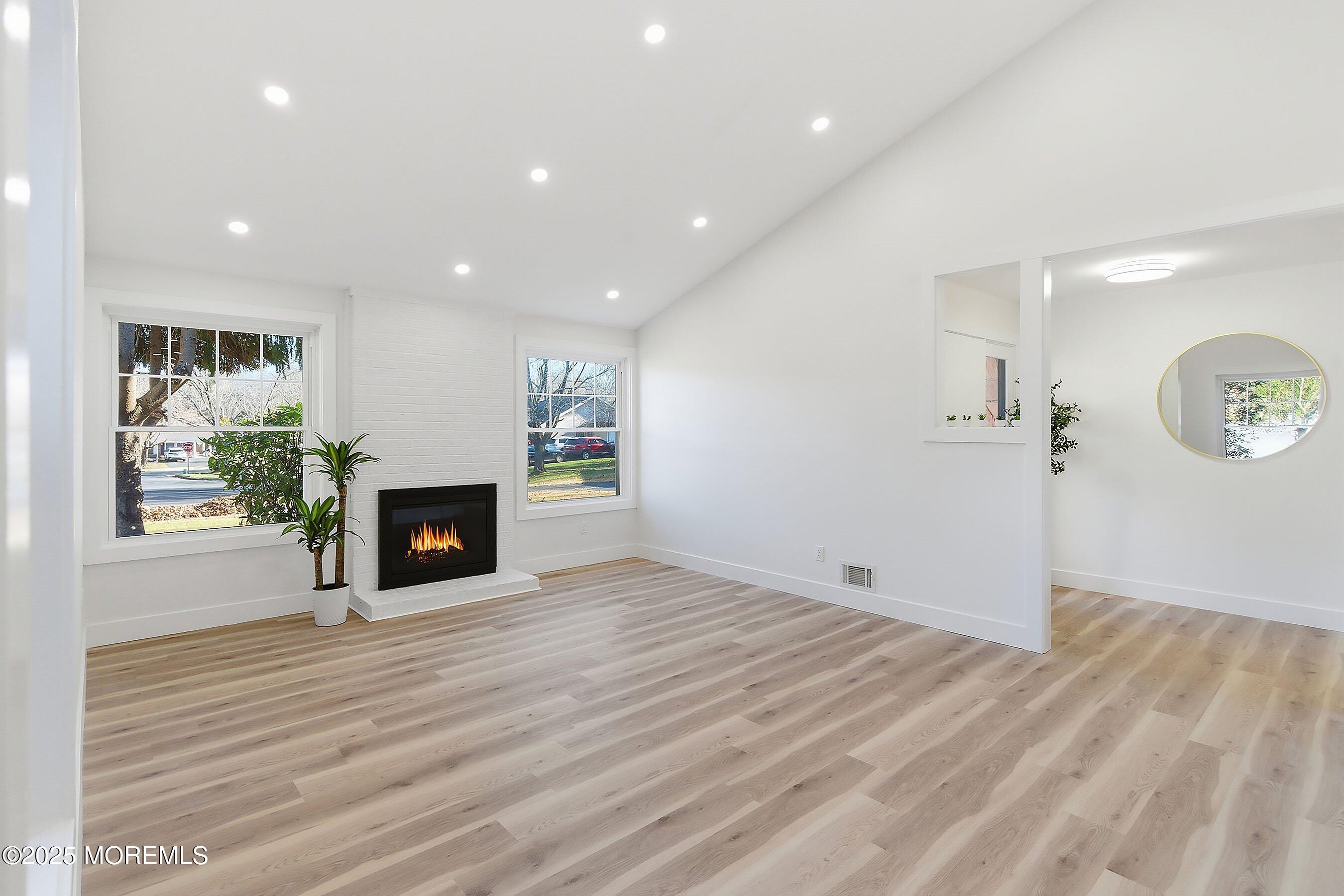 an empty room with wooden floor fireplace and windows