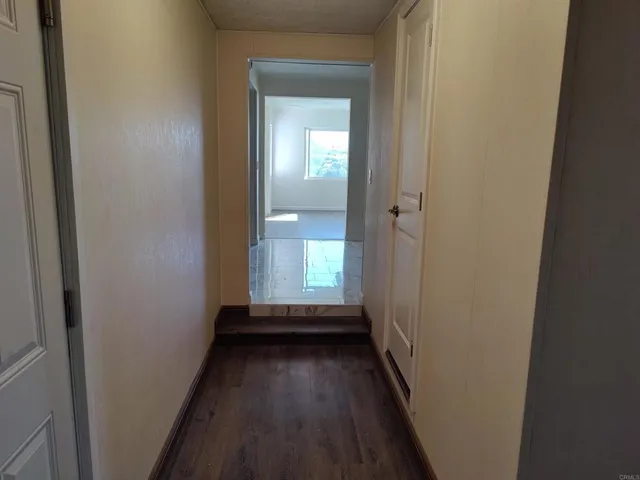 a view of a hallway with wooden floor and a bathroom