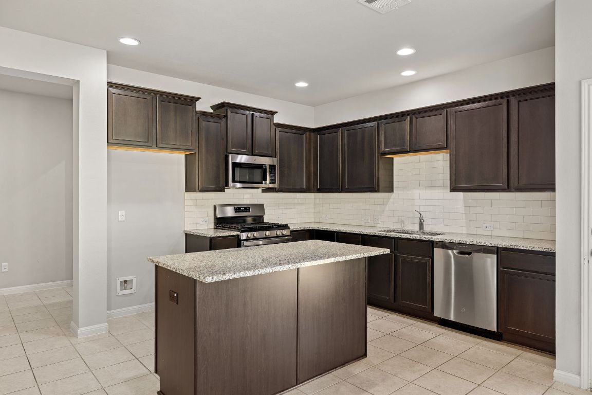 321 Arabian Colt Drive Georgetown, TX 78626 - Photo 8 of 24 a kitchen with stainless steel appliances granite countertop a sink stove microwave and refrigerator