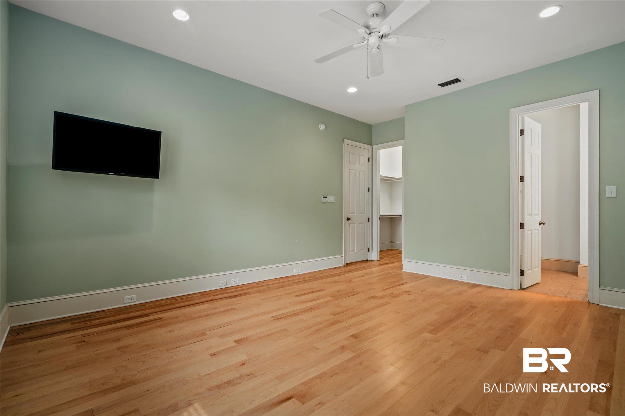 812 Country Club Court Mobile, AL 36609 - Photo 15 of 34 Unfurnished bedroom featuring ceiling fan, ensuite bath, a spacious closet, and light hardwood / wood-style floors