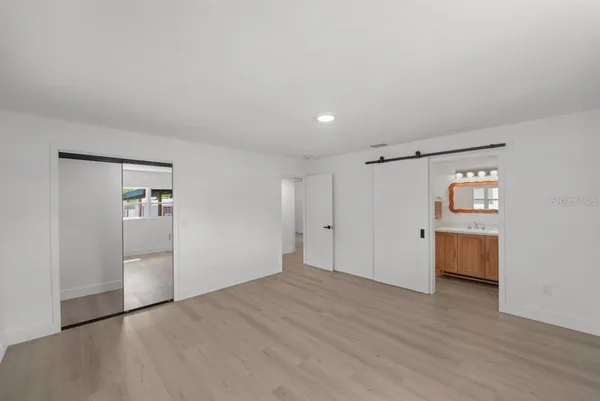 a view of an empty room with wooden floor and closet