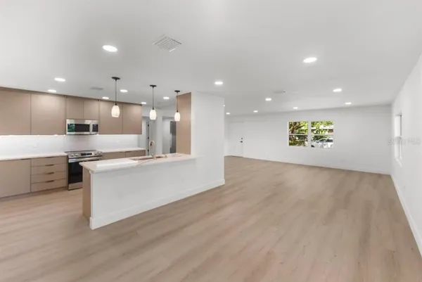 a large kitchen with a lot of counter top space a sink and stainless steel appliances