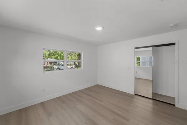 an empty room with wooden floor and windows