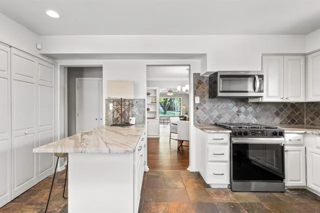 a kitchen with stainless steel appliances granite countertop a sink a stove and white cabinets