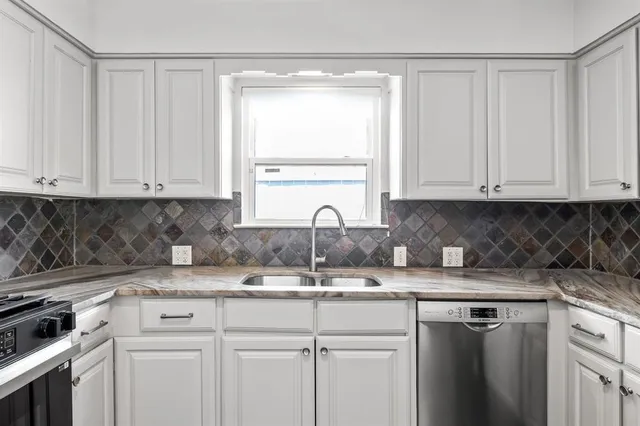 a kitchen with granite countertop white cabinets and stainless steel appliances
