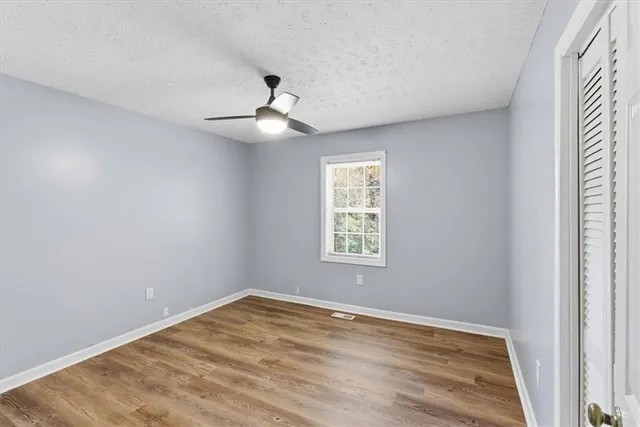 a view of empty room with wooden floor and fan