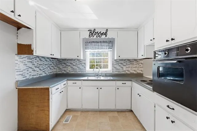 a kitchen with granite countertop white cabinets and a sink