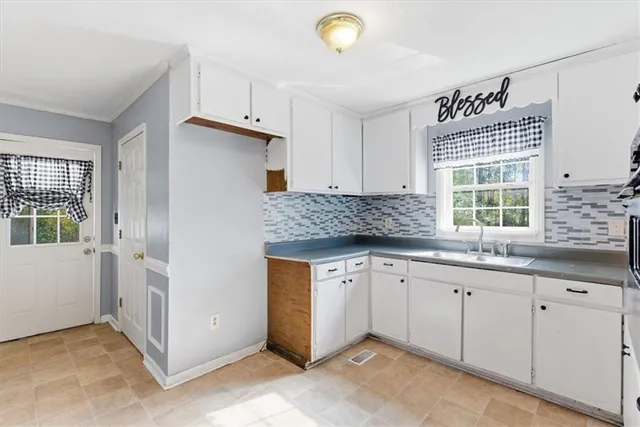 a kitchen with granite countertop a sink and white cabinets