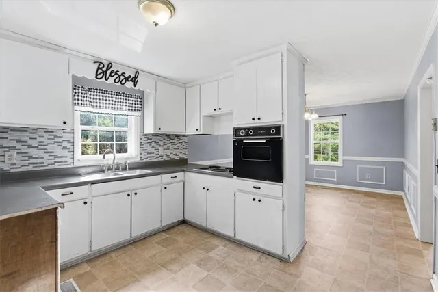 a kitchen with granite countertop a sink cabinets stainless steel appliances and a window
