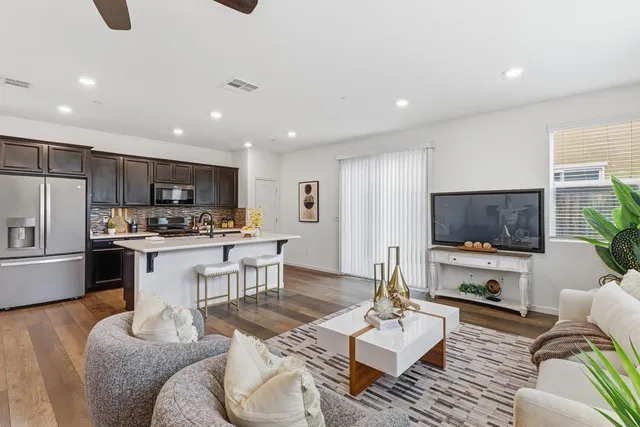 a kitchen with stainless steel appliances granite countertop a refrigerator a stove top oven a sink dishwasher and white cabinets with wooden floor