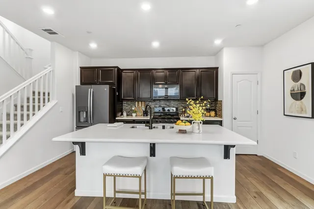 a kitchen with stainless steel appliances a stove top oven a refrigerator cabinets and a dining table