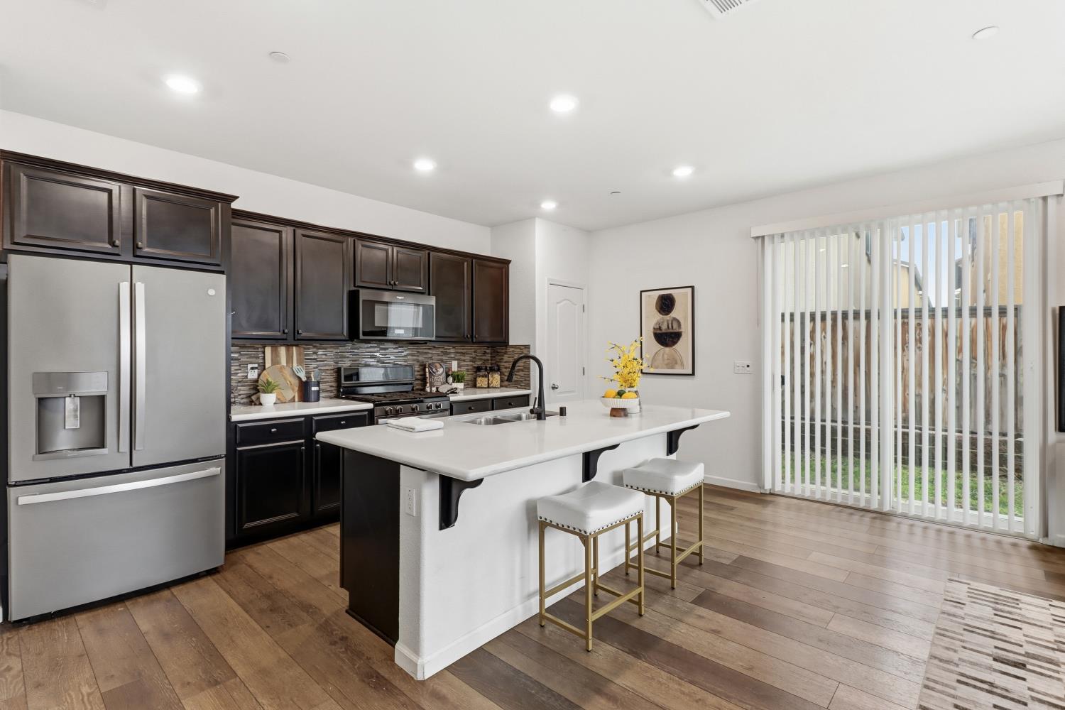 8900 Sheldon Terrace Lane Elk Grove, CA 95758 - Photo 18 of 57 a kitchen with stainless steel appliances a stove top oven a refrigerator cabinets and a dining table