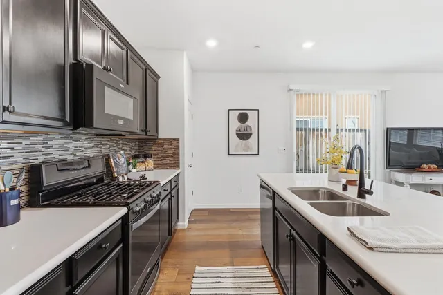 a kitchen with stainless steel appliances a stove a sink cabinets and a wooden floor