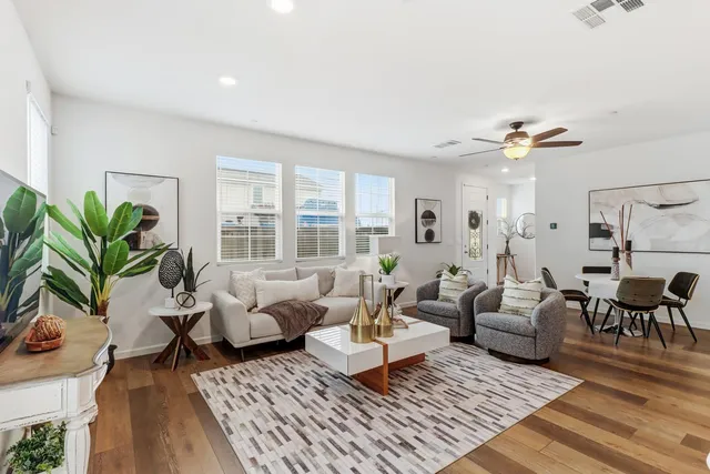 a living room with furniture kitchen view and a wooden floor