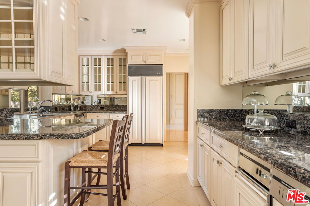 400 St Cloud Road Los Angeles, CA 90077 - Photo 17 of 25 a kitchen with stainless steel appliances granite countertop a stove a sink and a white cabinets
