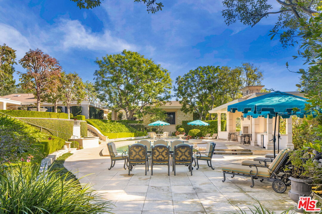 400 St Cloud Road Los Angeles, CA 90077 - Photo 7 of 25 a view of a swimming pool with a table and chairs under an umbrella