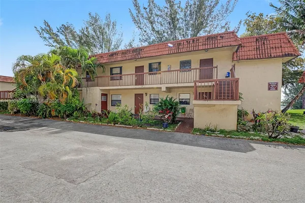 front view of house with potted plants and a yard