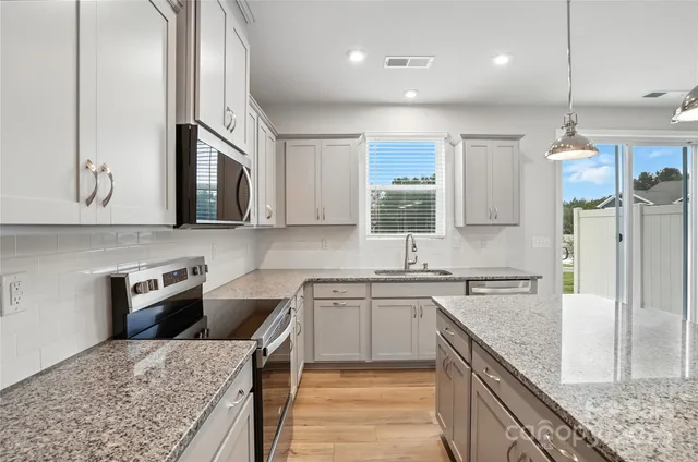 a kitchen with stainless steel appliances granite countertop a sink a stove and a refrigerator