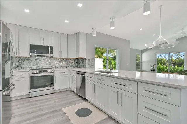 a kitchen with kitchen island granite countertop appliances cabinets and a sink