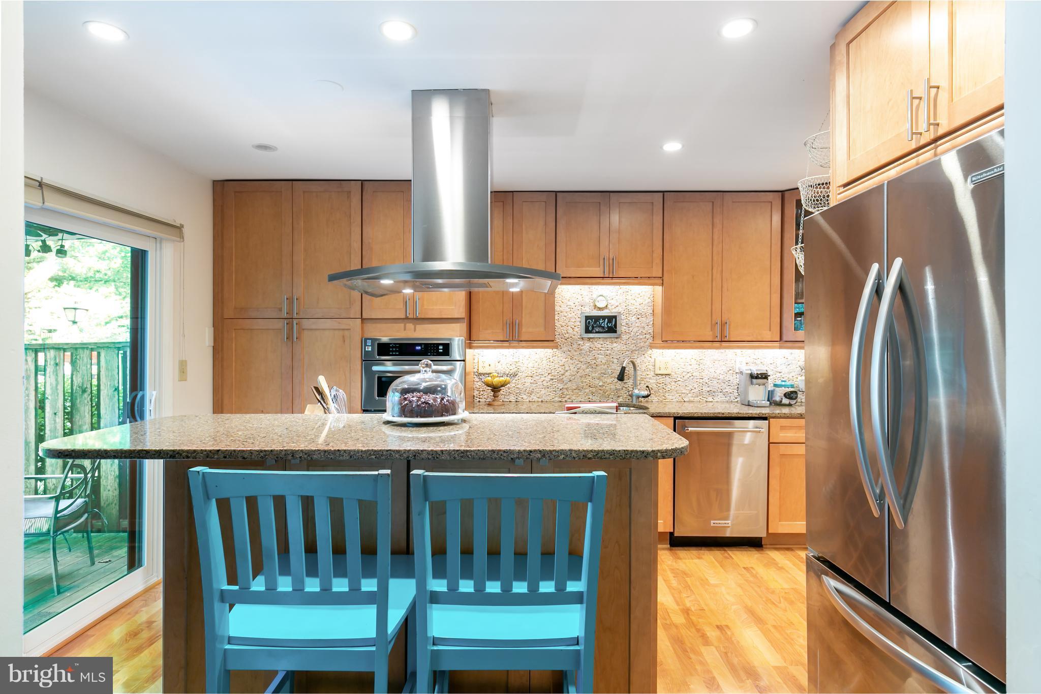a kitchen with stainless steel appliances granite countertop a refrigerator a stove and a sink with large window