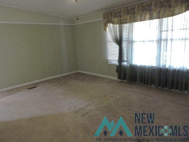 35 Mays Road Clayton, NM 88415 - Photo 25 of 31 Spacious room featuring light-colored carpet flooring, pale green wall paint, and white crown molding