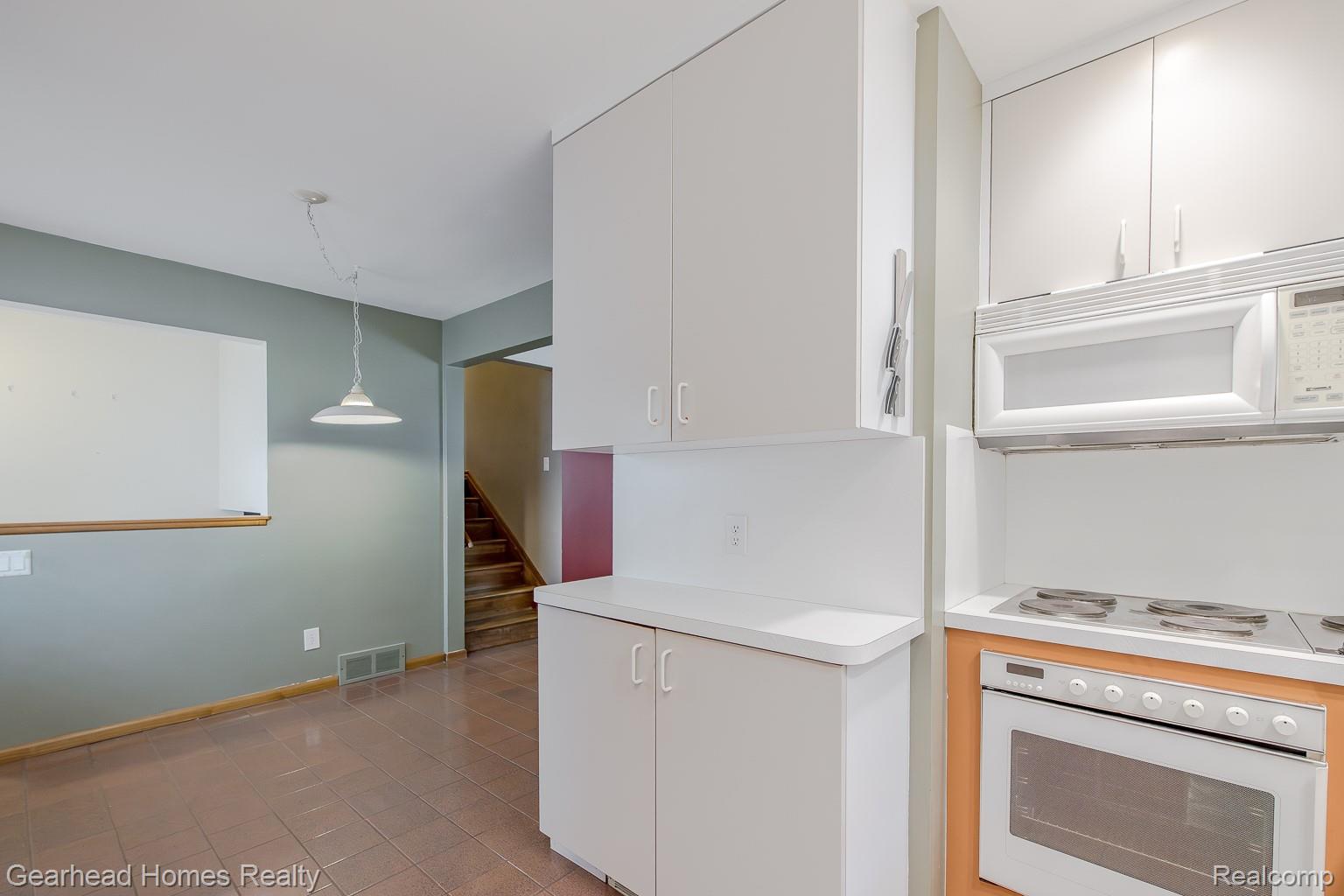 3356 Harding Street Dearborn, MI 48124 - Photo 15 of 48 White cabinetry with integrated appliances, including an oven and microwave, complemented by a white countertop