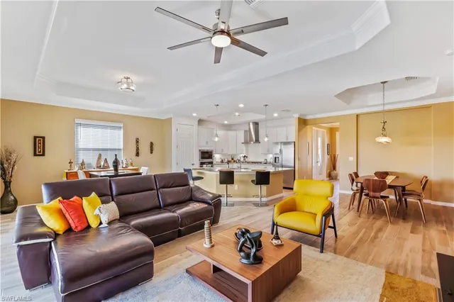 a living room with furniture kitchen view and a large window