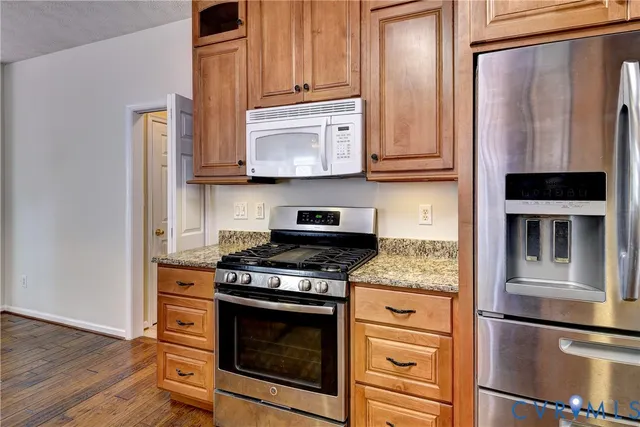 a kitchen with stainless steel appliances granite countertop a stove microwave and refrigerator