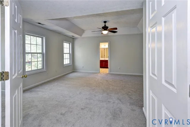 an empty room with windows and chandelier fan