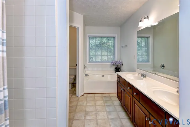 a spacious bathroom with a double vanity sink a mirror and a bathtub