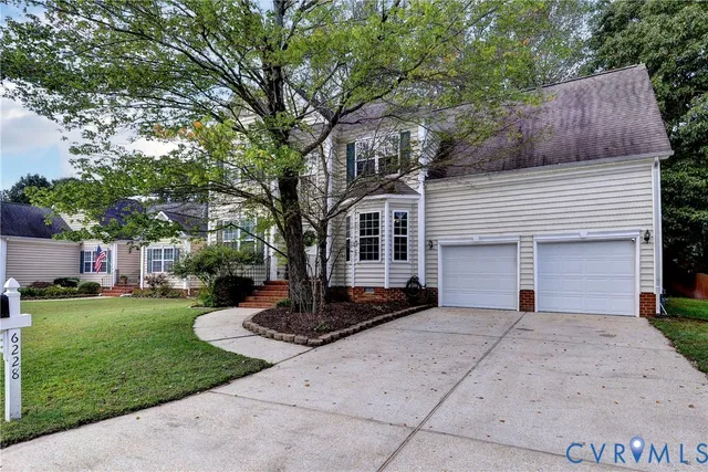 a front view of a house with a garden and trees