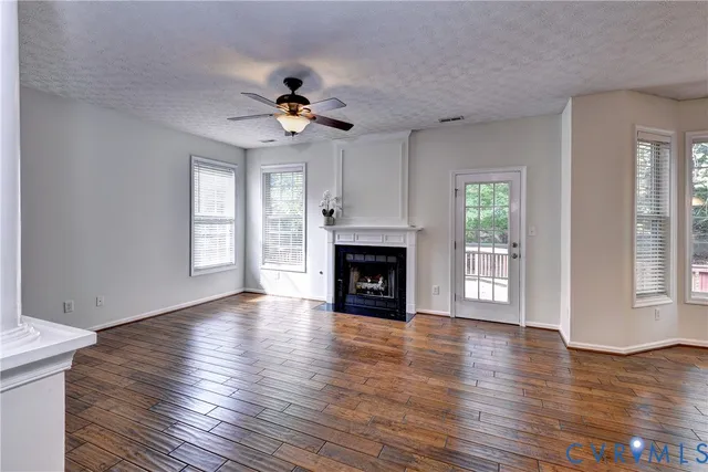 a view of an empty room with wooden floor fireplace and a window