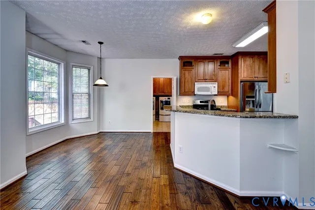 a kitchen with kitchen island a counter top space a sink a refrigerator and a view of living room