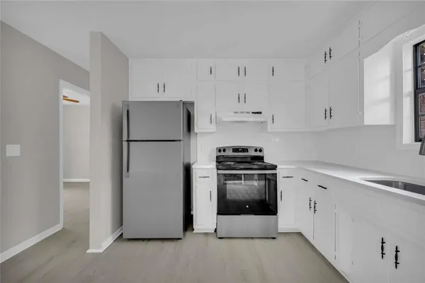 a kitchen with stainless steel appliances a refrigerator stove and white cabinets