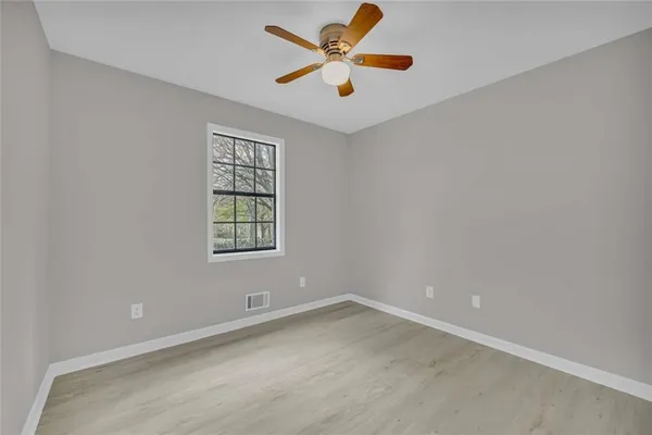 an empty room with a window and a fan
