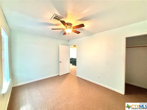 an empty room with a ceiling fan and a window