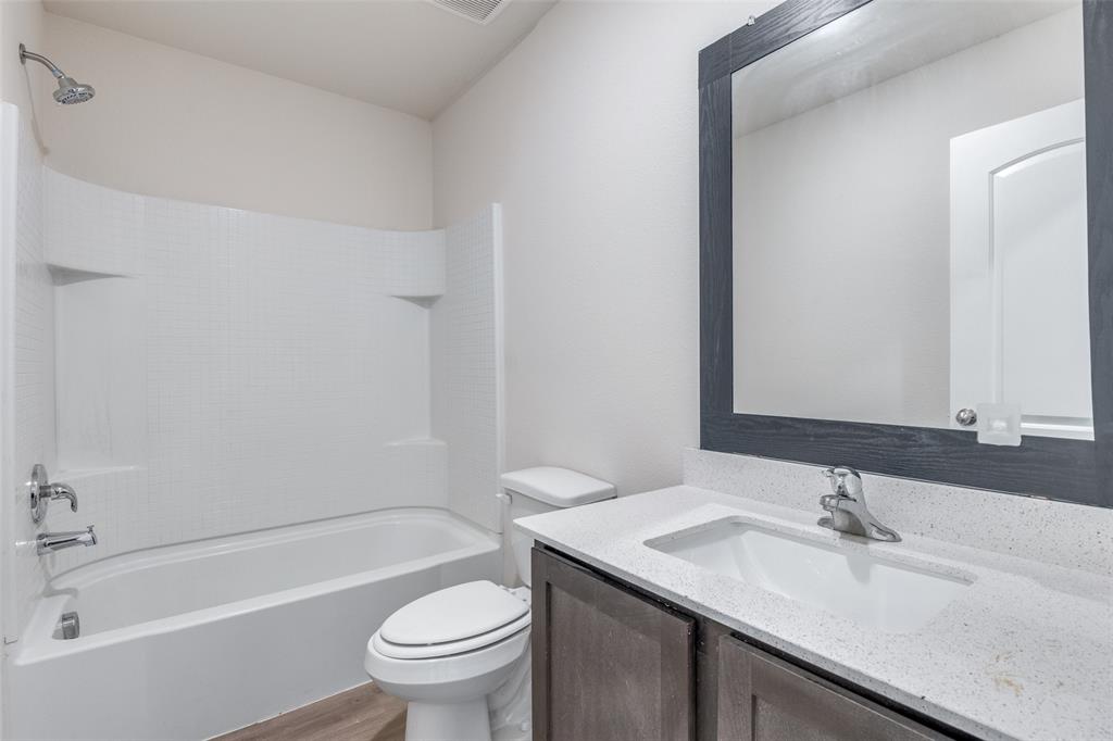 144 Barbwire Way Newark, TX 76071 - Photo 16 of 24 a bathroom with a granite countertop sink a toilet and a bathtub