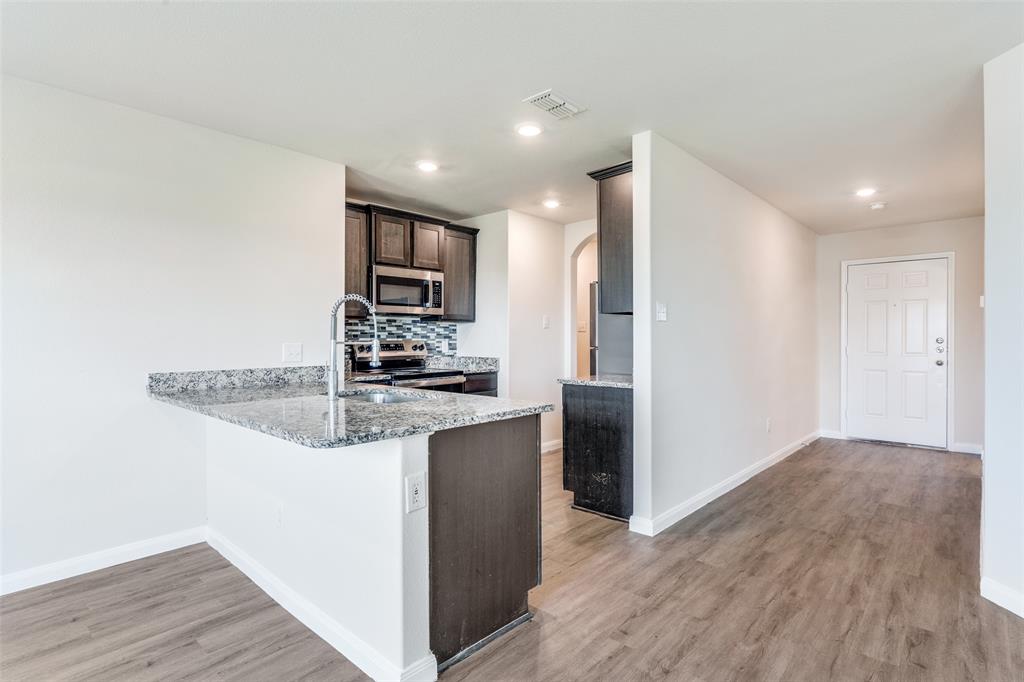 144 Barbwire Way Newark, TX 76071 - Photo 3 of 24 a kitchen with stainless steel appliances granite countertop a refrigerator and a stove top oven