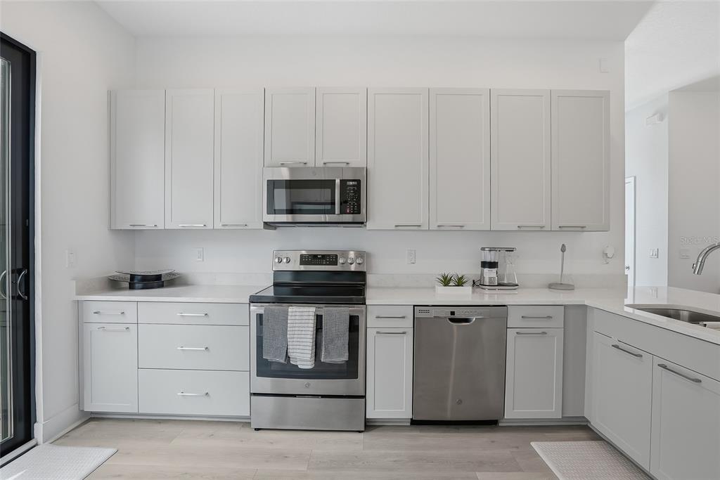 4810 West McElroy Avenue, Unit 30 Tampa, FL 33611 - Photo 3 of 43 a kitchen with stainless steel appliances granite countertop a stove a sink and white cabinets