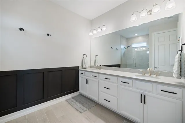 a bathroom with a granite countertop double vanity sink and mirror