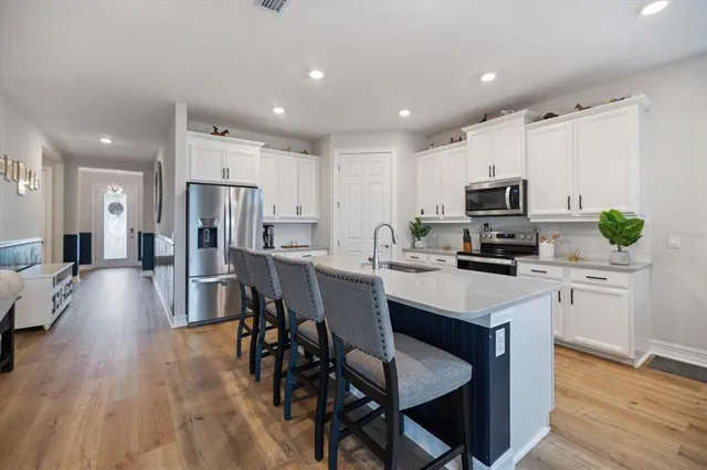 a kitchen with a sink a microwave a refrigerator and chairs