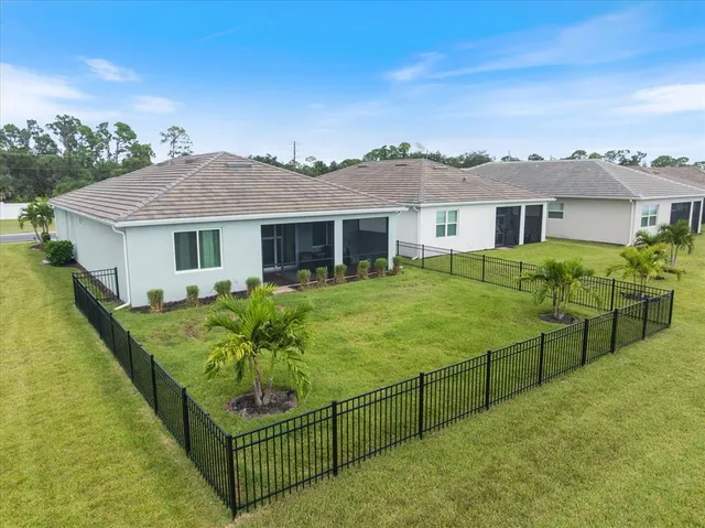 a view of a white house in front of a big yard and potted plants