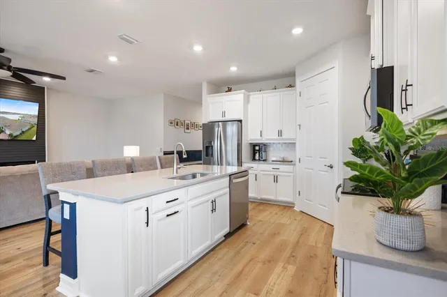 a kitchen that has a lot of white cabinets and wooden floor